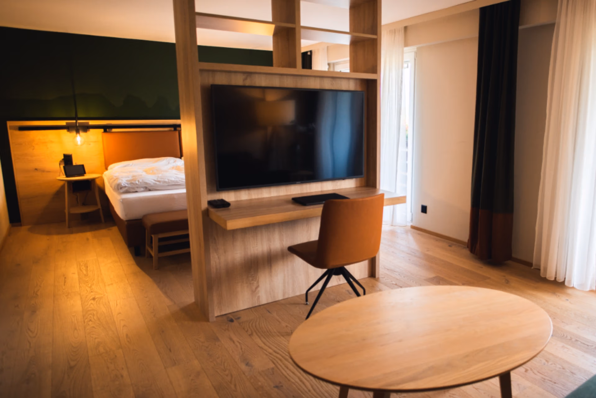 Hotelzimmer mit Bett, Schreibtisch und Holzboden